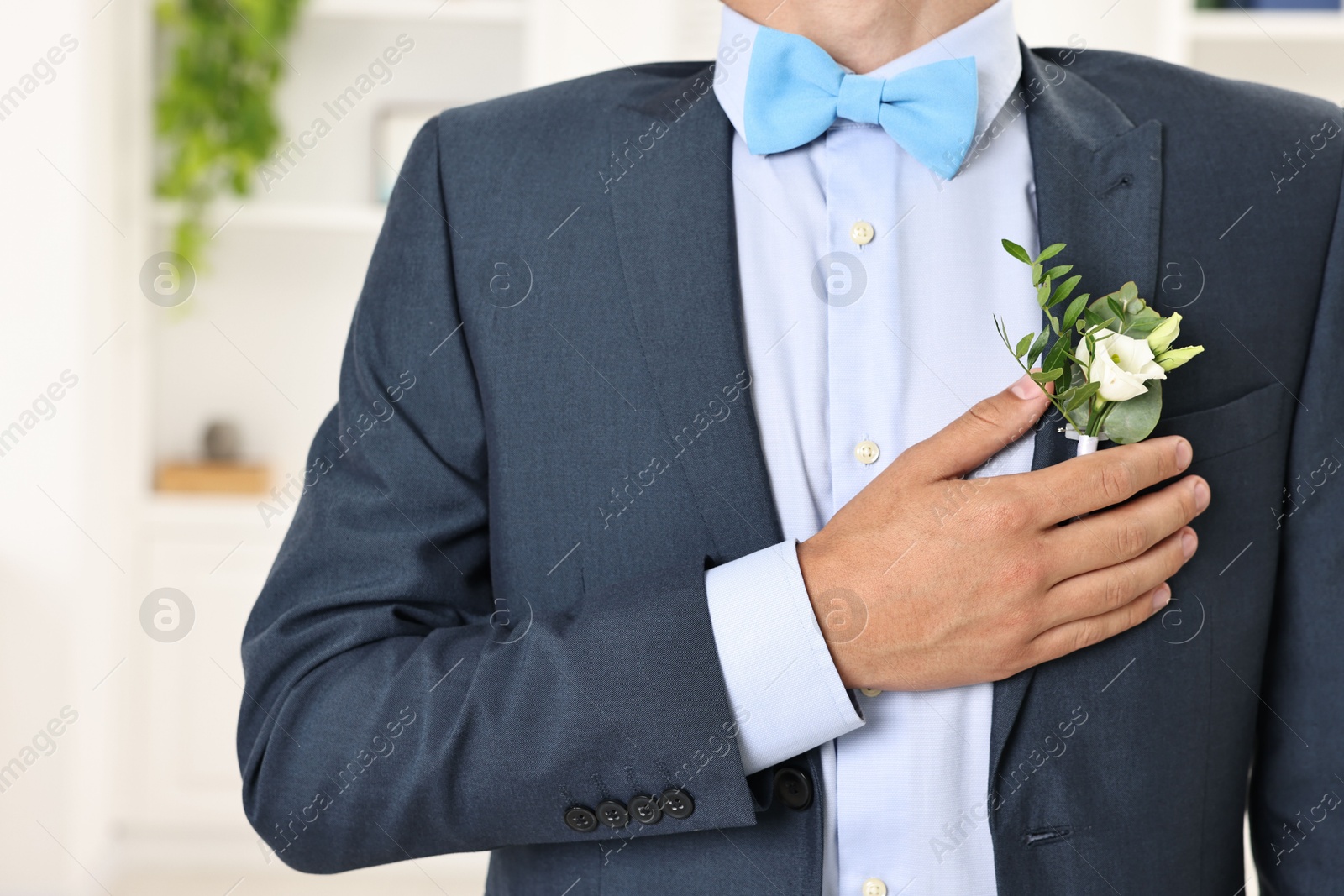 Photo of Groom in suit with stylish boutonniere indoors, closeup