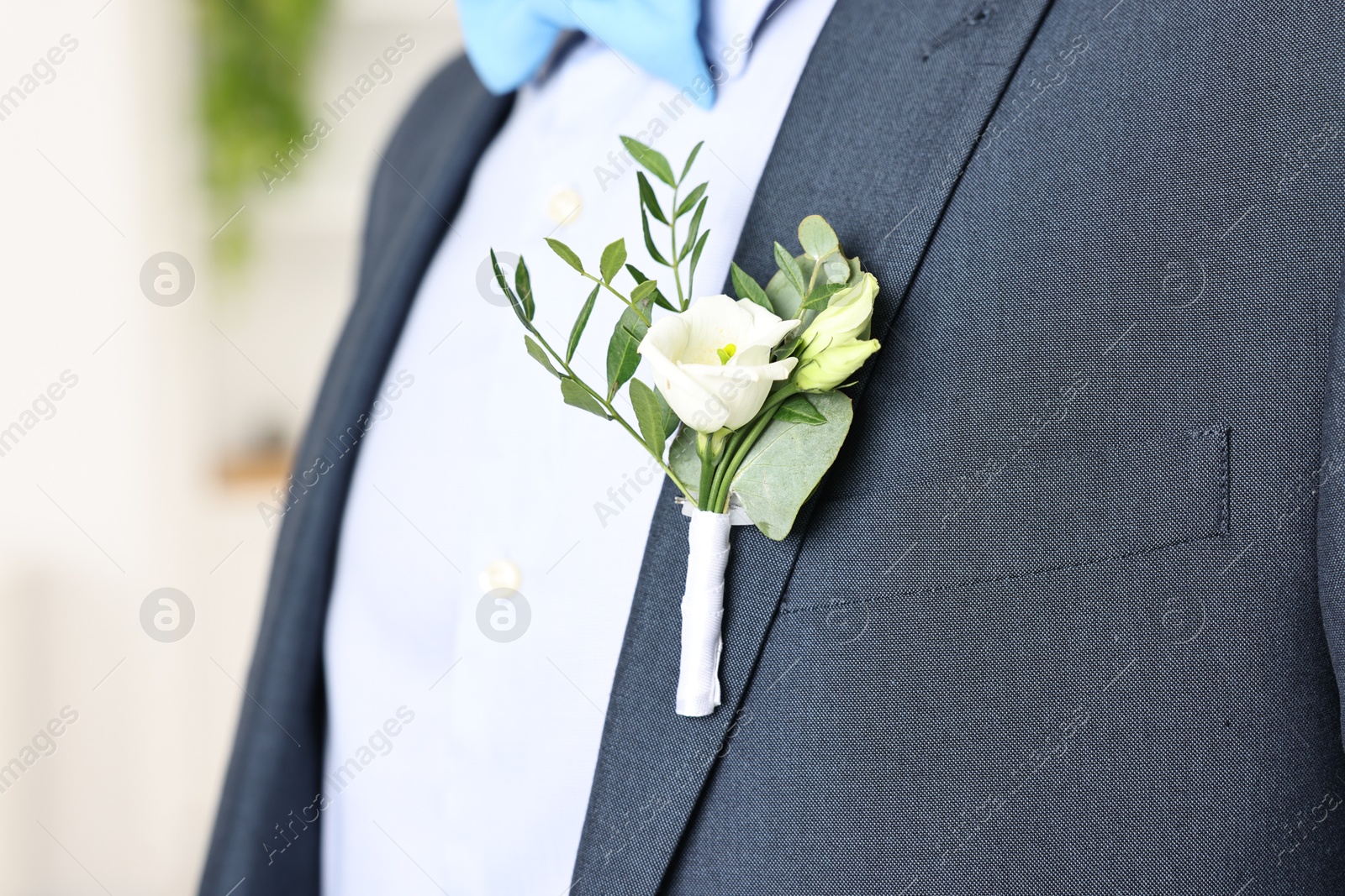 Photo of Groom in suit with stylish boutonniere indoors, closeup