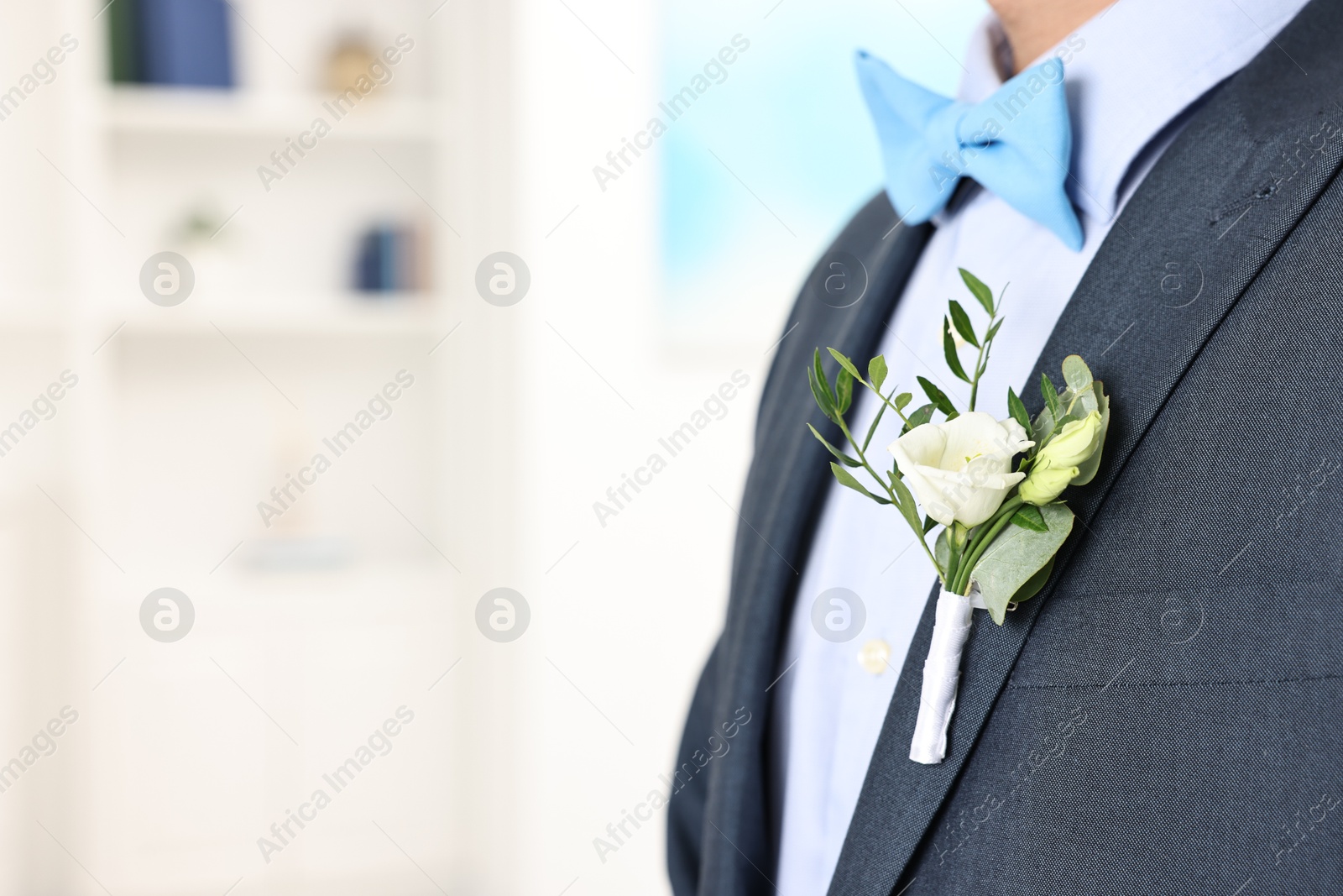 Photo of Groom in suit with stylish boutonniere indoors, closeup. Space for text