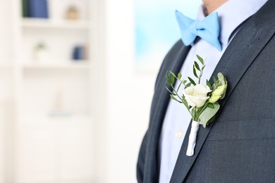 Photo of Groom in suit with stylish boutonniere indoors, closeup. Space for text