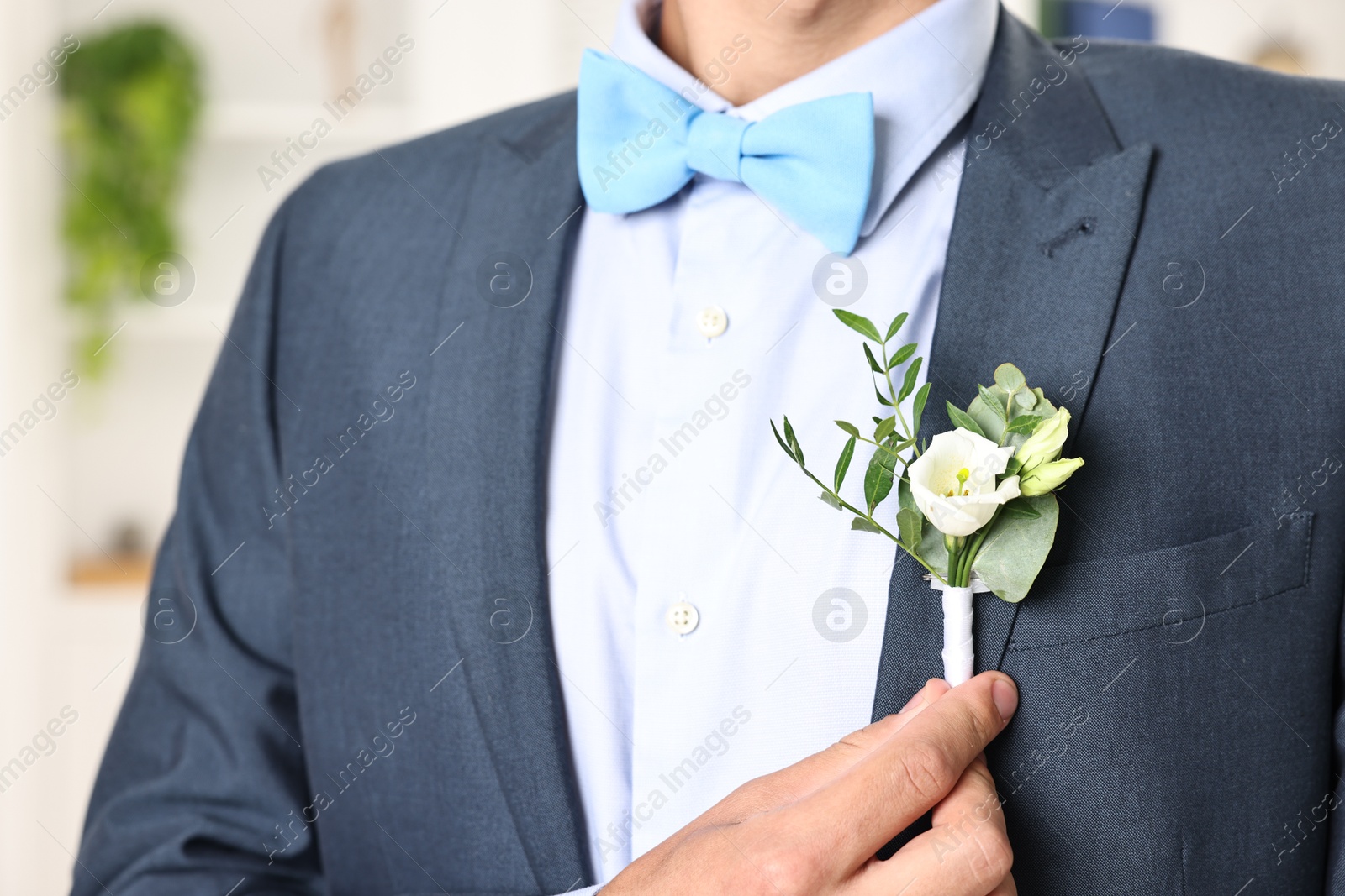 Photo of Groom in suit with stylish boutonniere indoors, closeup