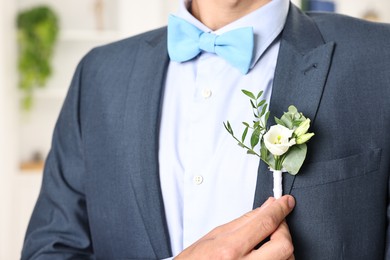 Photo of Groom in suit with stylish boutonniere indoors, closeup