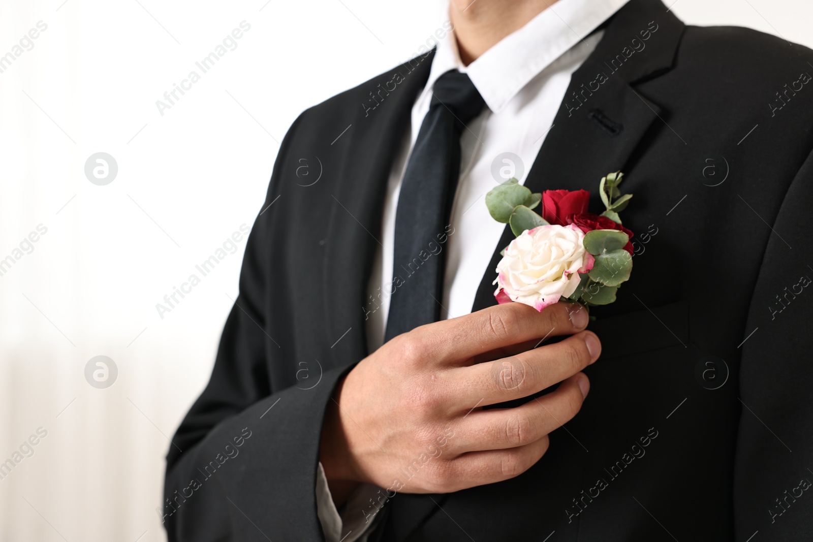 Photo of Groom in suit with stylish boutonniere indoors, closeup