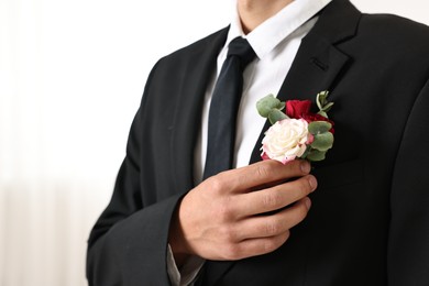 Photo of Groom in suit with stylish boutonniere indoors, closeup