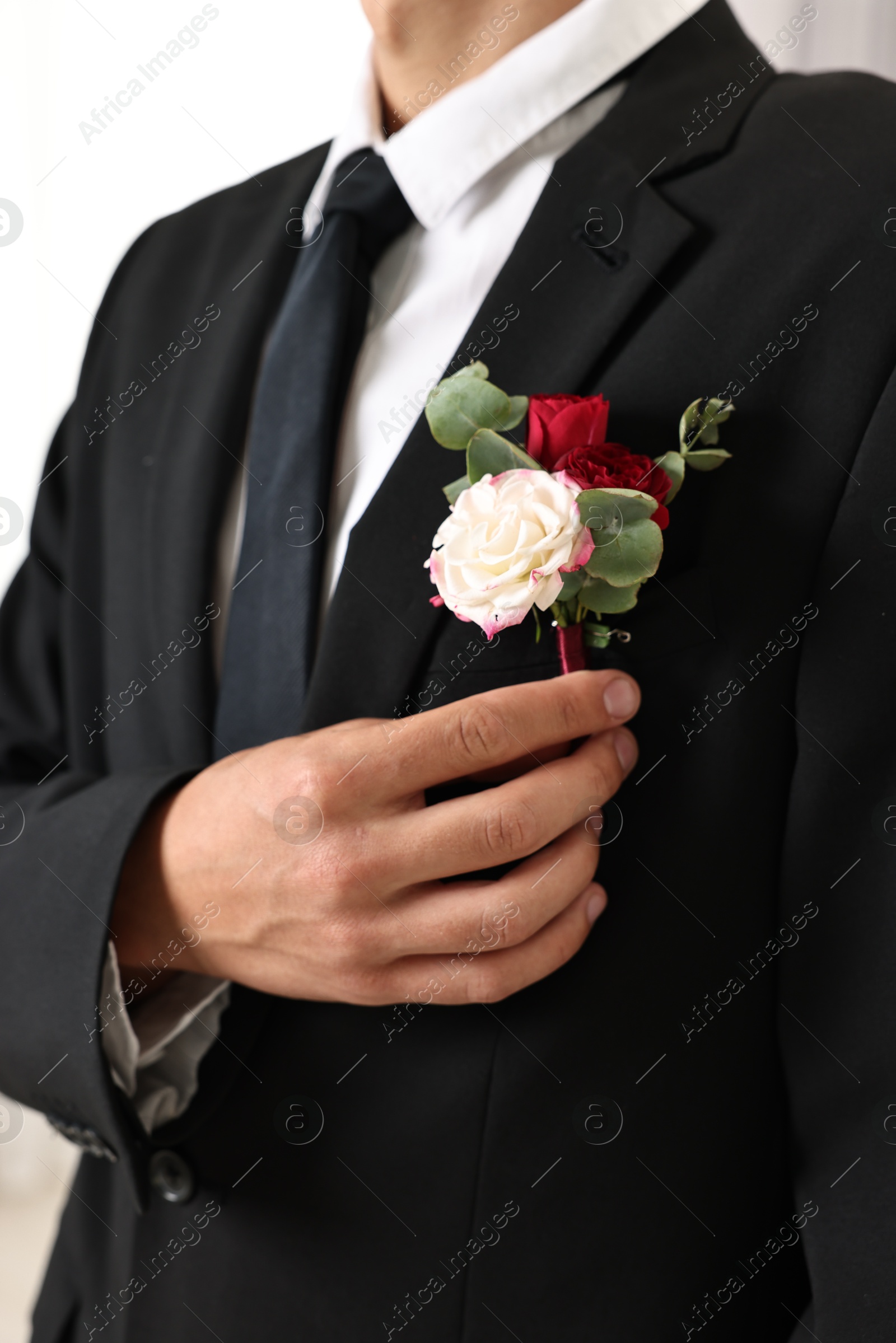 Photo of Groom in suit with stylish boutonniere indoors, closeup