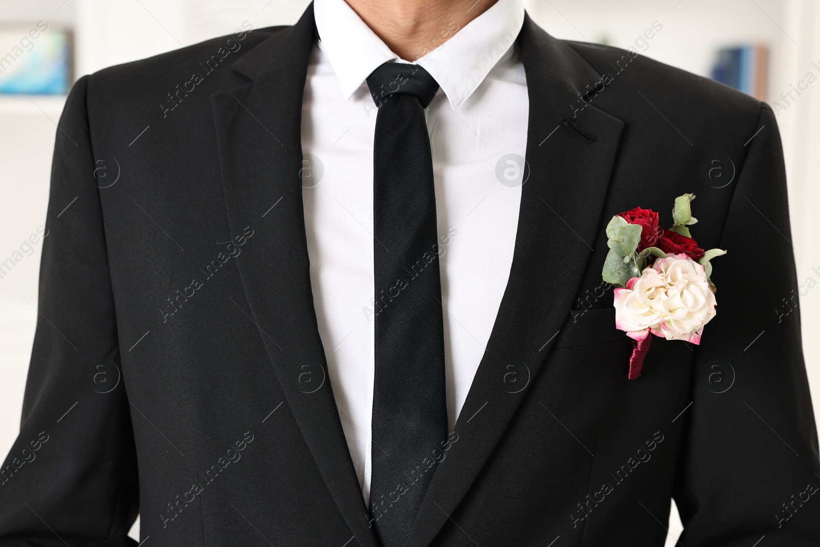 Photo of Groom in suit with stylish boutonniere indoors, closeup