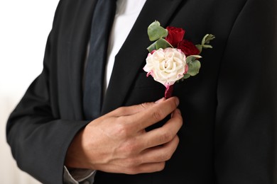 Photo of Groom in suit with stylish boutonniere indoors, closeup