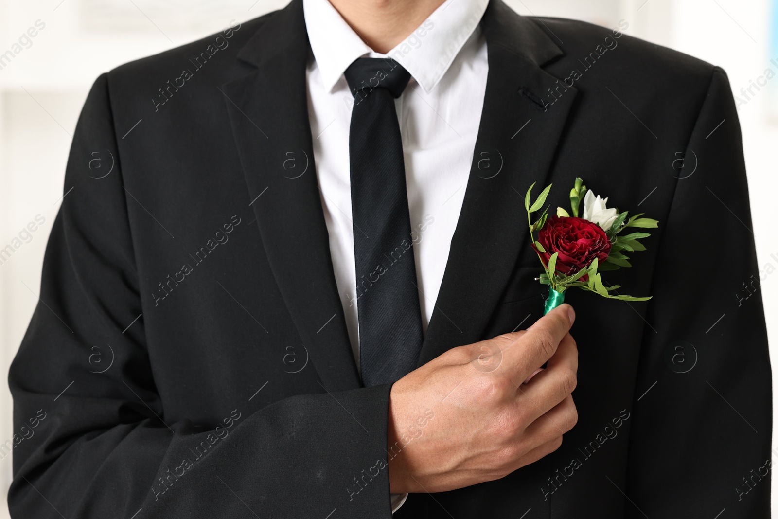 Photo of Groom in suit with stylish boutonniere indoors, closeup