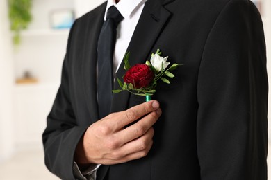 Photo of Groom in suit with stylish boutonniere indoors, closeup