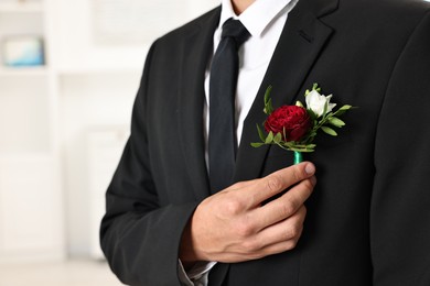 Photo of Groom in suit with stylish boutonniere indoors, closeup