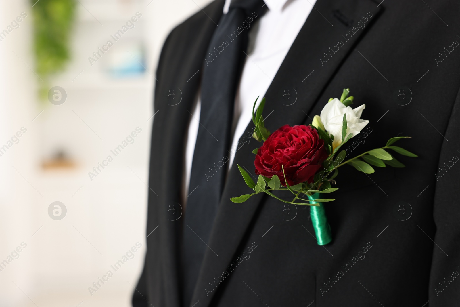 Photo of Groom in suit with stylish boutonniere indoors, closeup