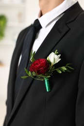 Photo of Groom in suit with stylish boutonniere indoors, closeup