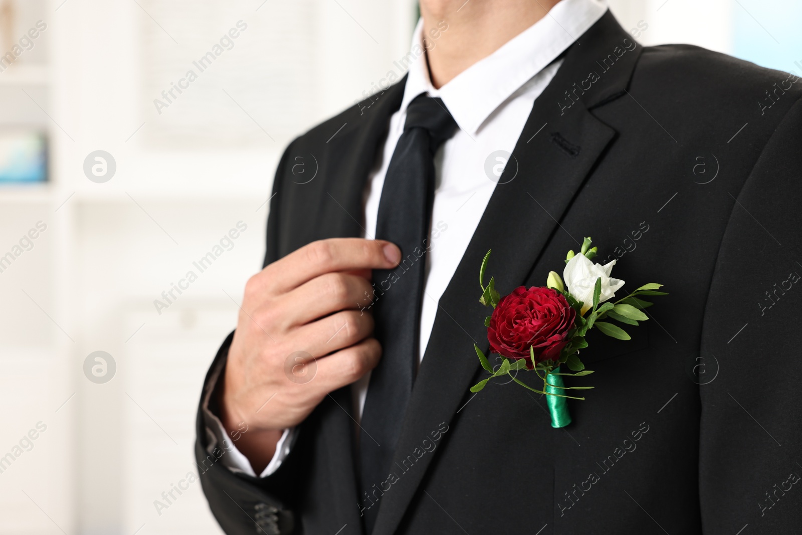 Photo of Groom in suit with stylish boutonniere indoors, closeup