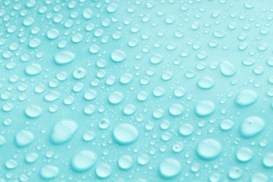 Photo of Water drops on turquoise background, closeup view