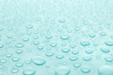 Photo of Water drops on turquoise background, closeup view