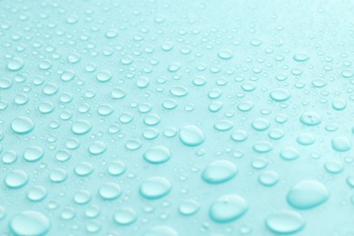 Photo of Water drops on turquoise background, closeup view