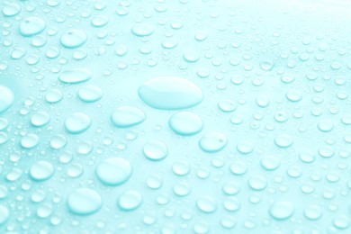 Photo of Water drops on turquoise background, closeup view