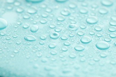 Photo of Water drops on turquoise background, closeup view