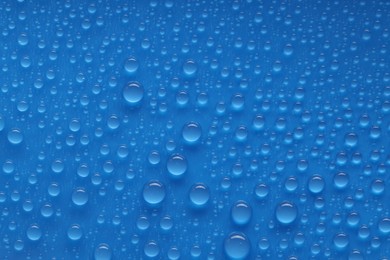 Photo of Water drops on blue background, top view