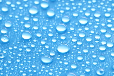 Photo of Water drops on blue background, closeup view