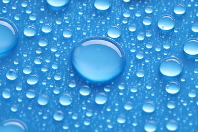 Photo of Water drops on blue background, closeup view