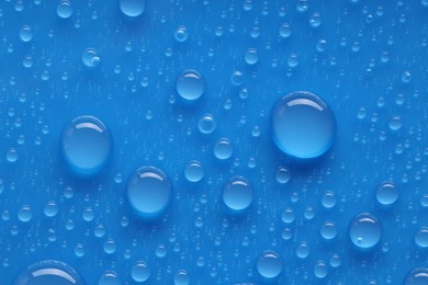 Photo of Water drops on blue background, top view