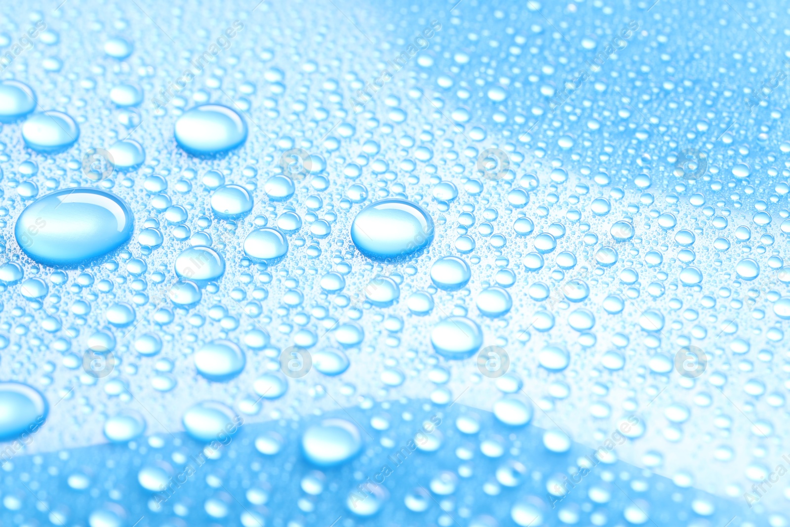 Photo of Water drops on light blue background, closeup