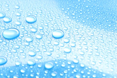 Photo of Water drops on light blue background, closeup