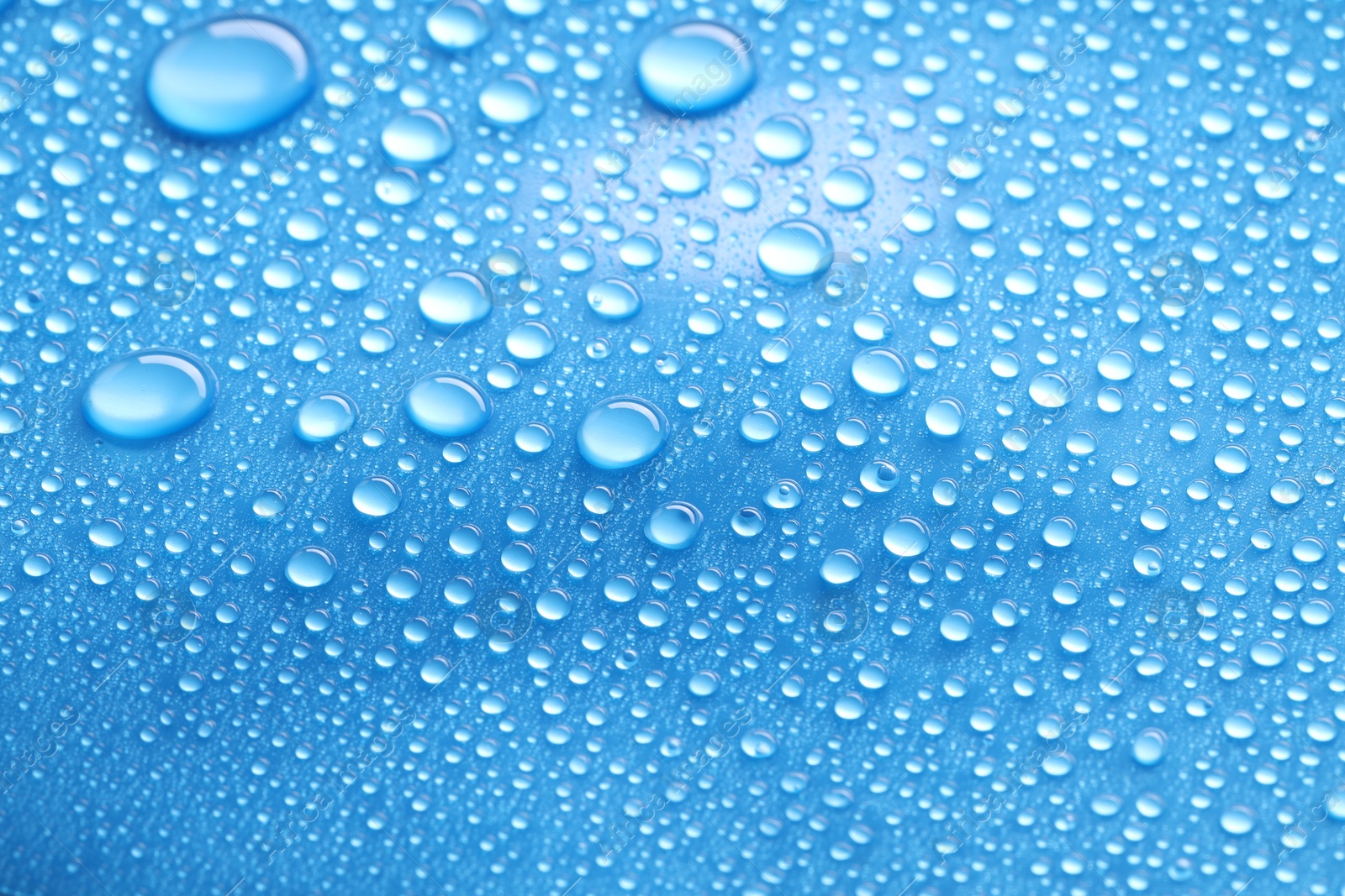 Photo of Water drops on blue background, closeup view