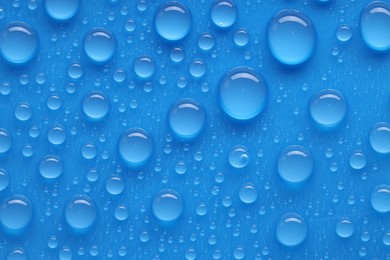 Photo of Water drops on blue background, top view