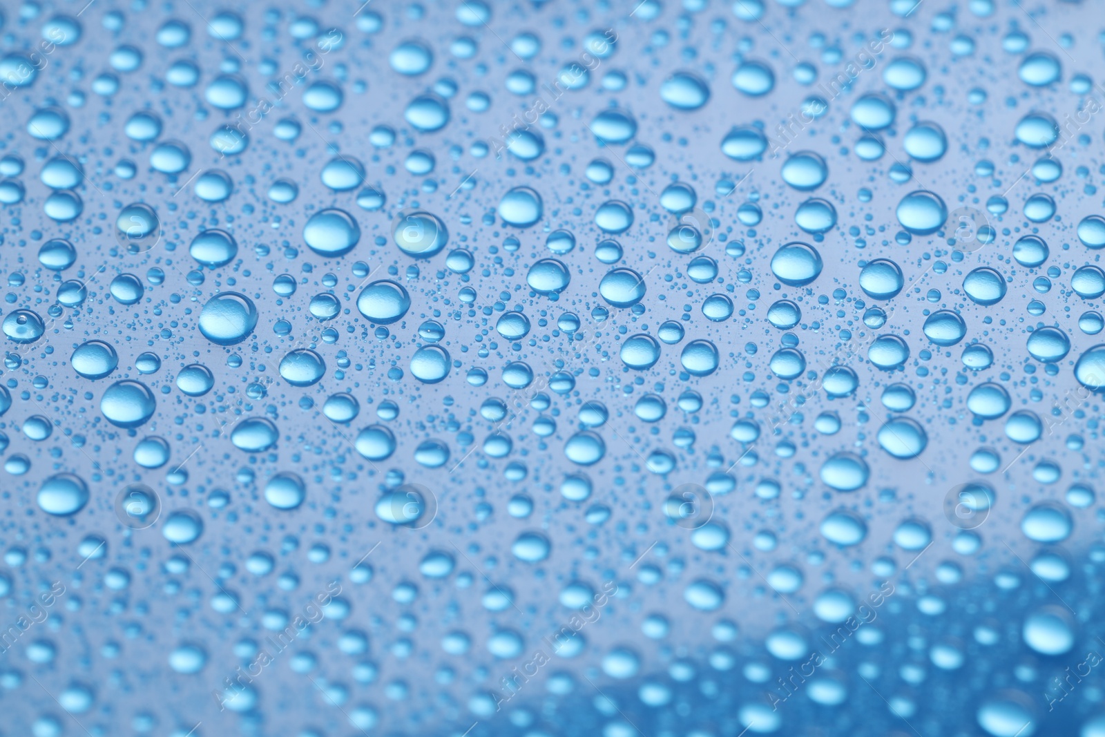 Photo of Water drops on blue background, closeup view