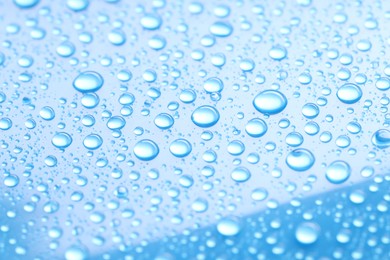 Photo of Water drops on light blue background, closeup