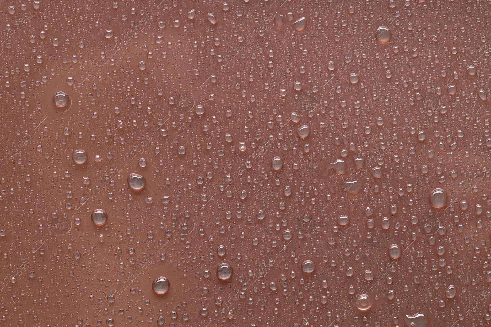 Photo of Water drops on brown background, top view