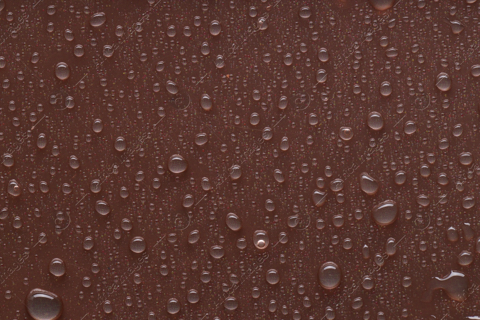 Photo of Water drops on brown background, top view