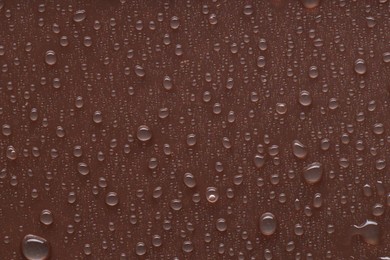 Photo of Water drops on brown background, top view