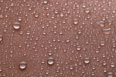 Photo of Water drops on brown background, closeup view