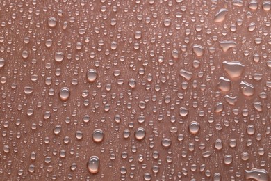 Photo of Water drops on brown background, top view