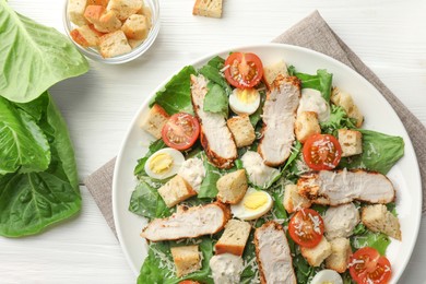 Photo of Tasty Caesar salad with chicken and tomatoes on white wooden table, flat lay