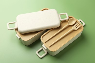 Compartments of plastic lunch box with cutlery on green background