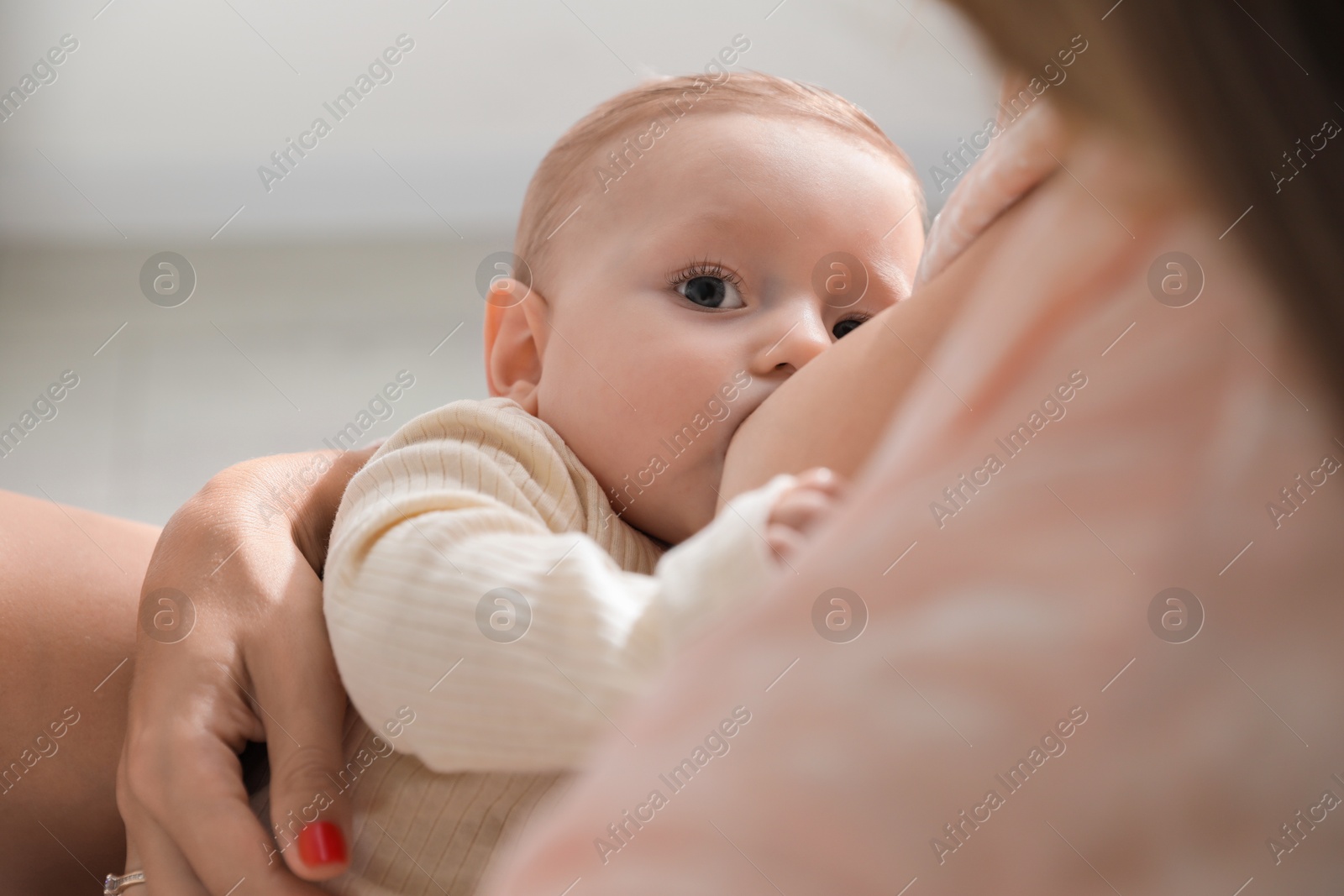 Photo of Mother breastfeeding her little baby indoors, closeup