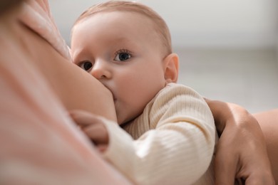 Photo of Mother breastfeeding her little baby indoors, closeup