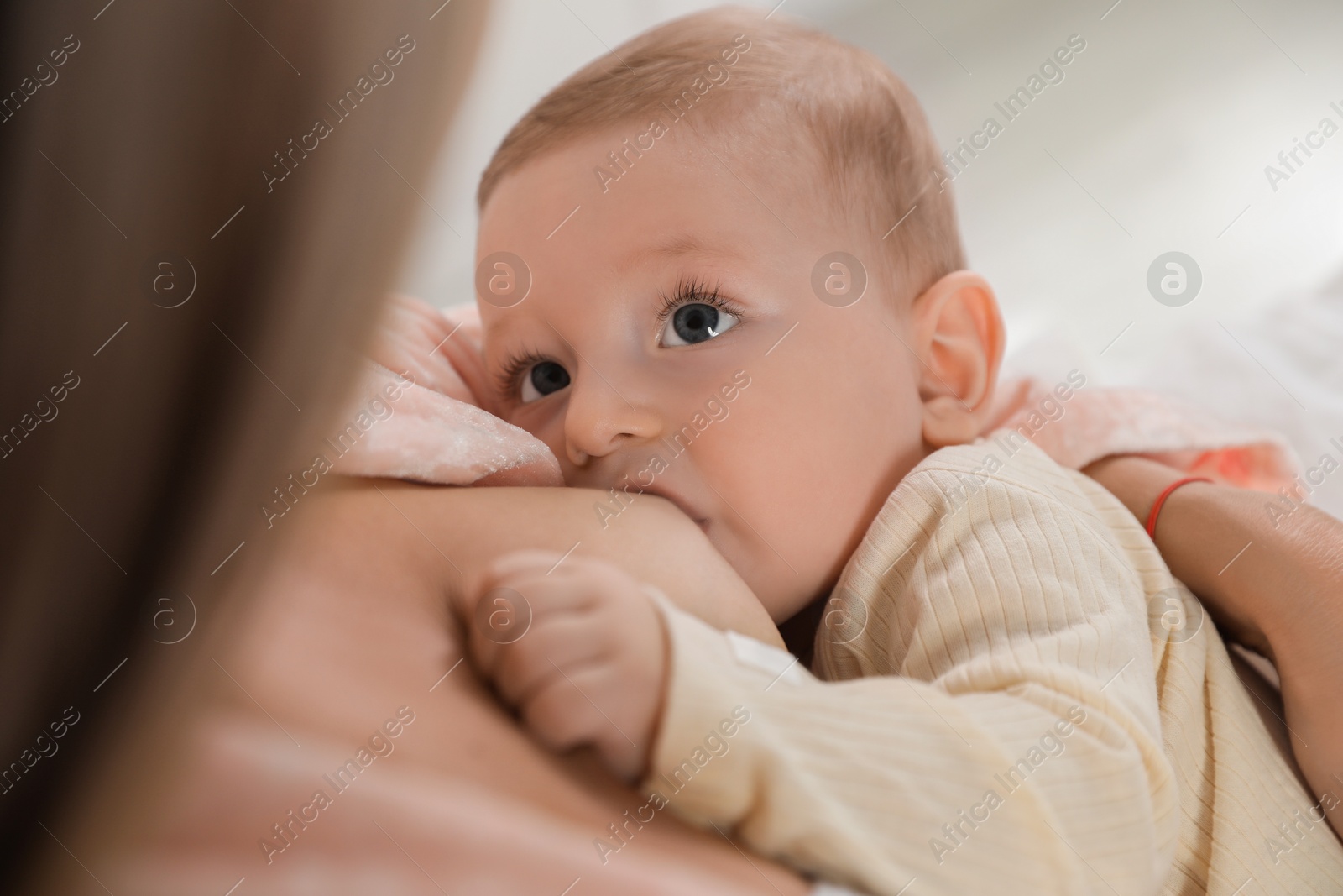 Photo of Mother breastfeeding her little baby indoors, closeup