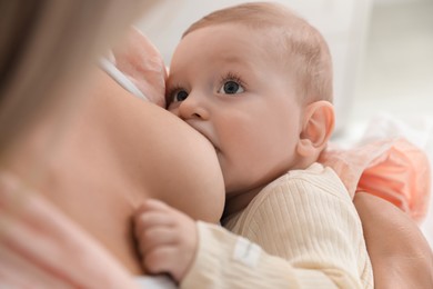 Photo of Mother breastfeeding her little baby indoors, closeup