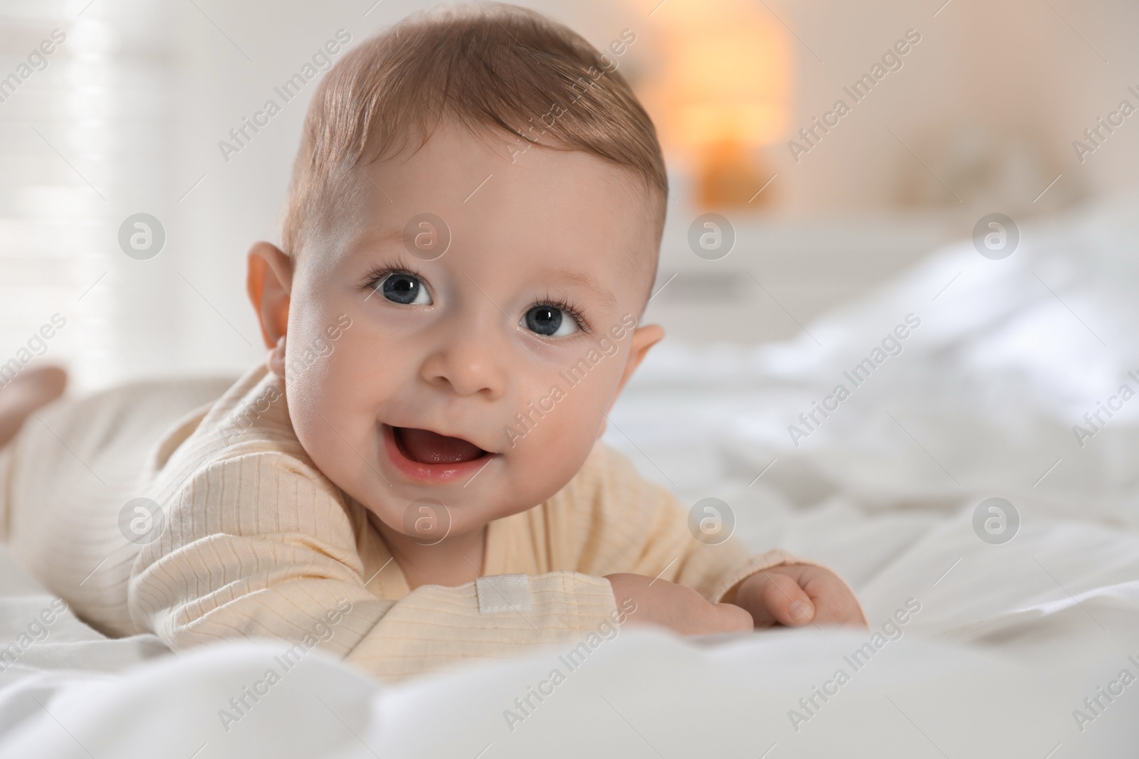 Photo of Cute little baby with pacifier on bed indoors