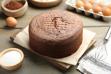 Tasty chocolate sponge cake and ingredients on wooden table, closeup