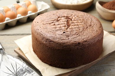 Photo of Tasty chocolate sponge cake and ingredients on wooden table, closeup