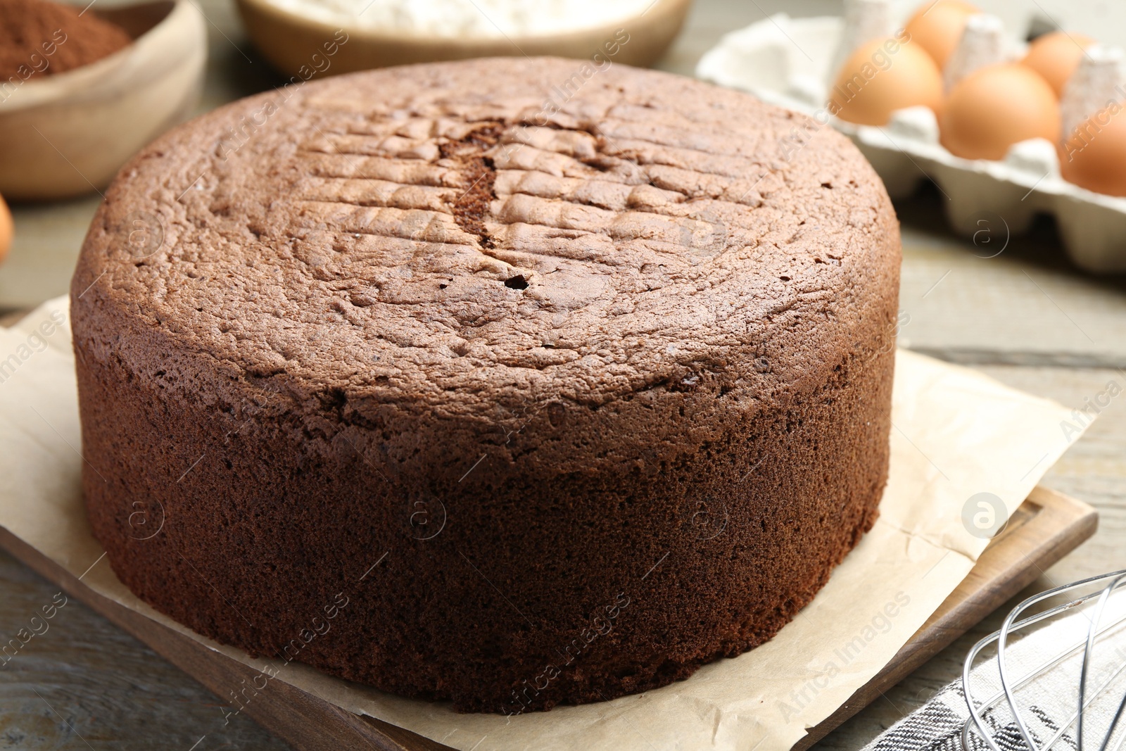 Photo of Tasty chocolate sponge cake and ingredients on wooden table, closeup