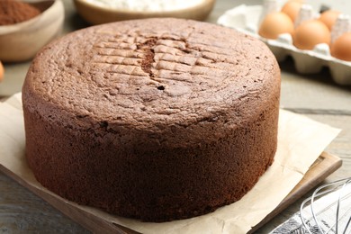 Photo of Tasty chocolate sponge cake and ingredients on wooden table, closeup