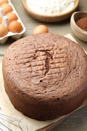 Photo of Tasty chocolate sponge cake and ingredients on wooden table, closeup