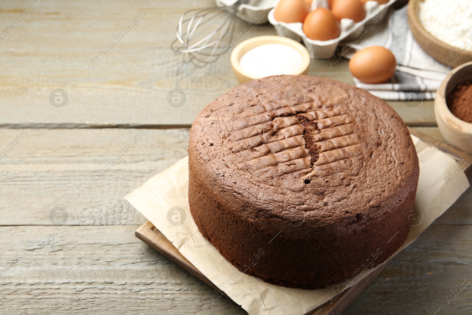 Photo of Tasty chocolate sponge cake and ingredients on wooden table, closeup. Space for text